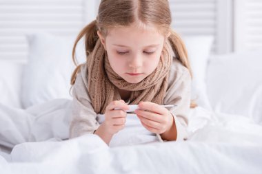 yatakta yatan ve termometre evde seyir boyun üzerinden eşarp ile hasta çocuk