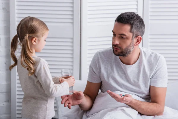 Dochter Glas Water Geven Aan Vader Pillen Nemen Slaapkamer — Stockfoto