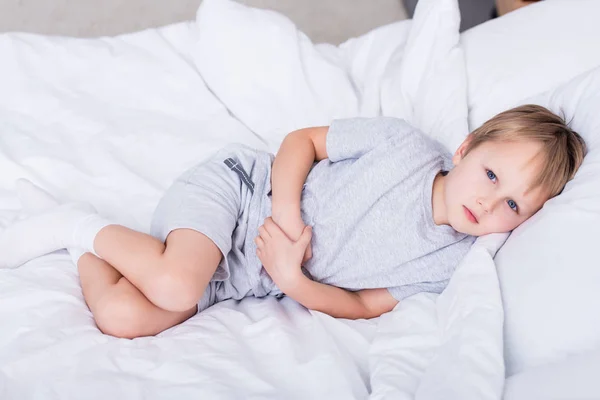 Sick Boy Lying Bed Touching Painful Stomach Bedroom Looking Camera — Stock Photo, Image