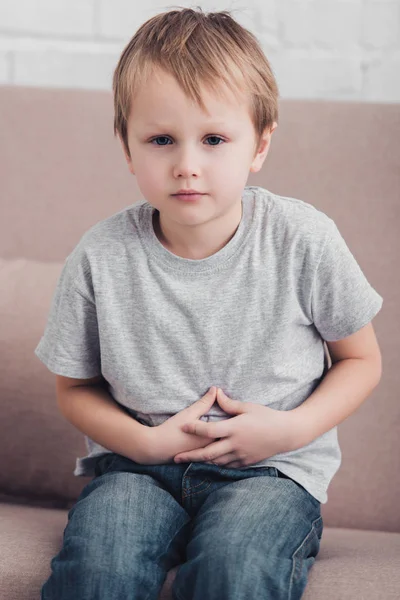 Chory Chłopiec Bólem Żołądka Siedząc Kanapie Salonie Patrząc Kamery — Zdjęcie stockowe