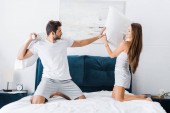young couple having pillow fight in bed 