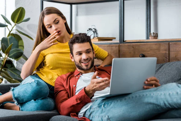 Jovem Casal Surpreso Sentado Sofá Usando Laptop — Fotografia de Stock