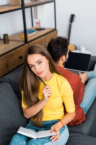 Thoughtful Woman Sitting Sofa Notebook Pen Boyfriend — Free Stock Photo