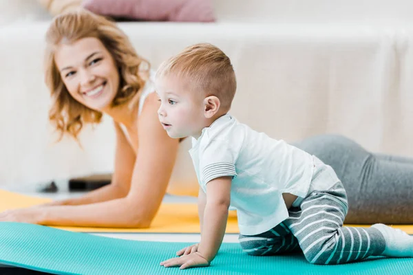 Frau Liegt Auf Teppich Und Lächelt Entzückendem Jungen — Stockfoto