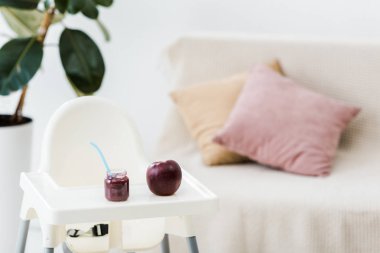 Salon sandalyesi üzerinde kaşıkla kırmızı elma ve bebek maması kavanoz