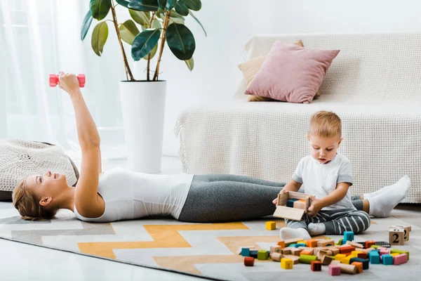 Attractive Woman Lying Carpet Exercising Dumbbells Cute Toddler Boy Holding — Stock Photo, Image