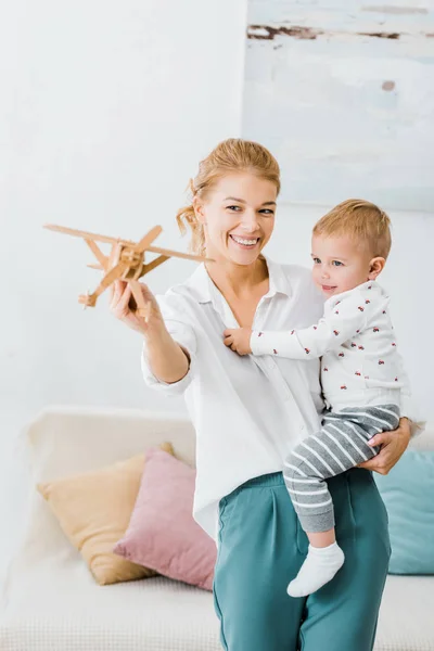 Lächelnde Frau Hält Holzflugzeug Modell Und Spielt Mit Entzückendem Kleinkind — Stockfoto
