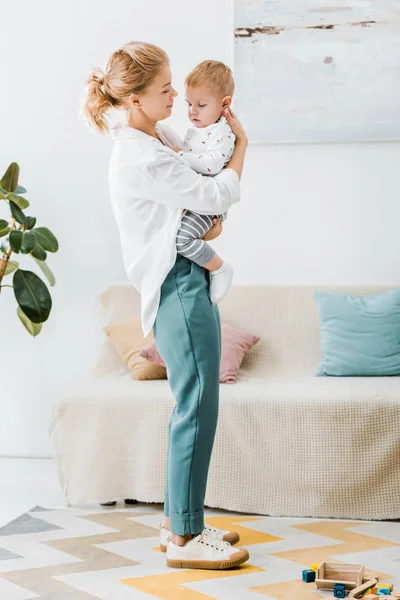 Atractiva Madre Pie Abrazando Adorable Hijo Pequeño Sala Estar —  Fotos de Stock