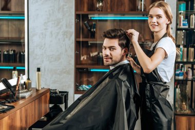 Genç kuaför ve güzellik salonu kameraya gülümseyen erkek istemci