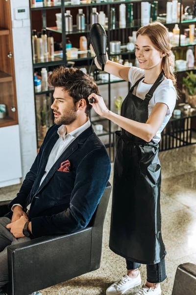 Visão Alto Ângulo Cabelo Secagem Cabeleireiro Feminino Sorridente Para Jovem — Fotografia de Stock