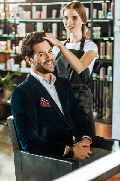Uśmiechnięta Młoda Fryzjerka Robi Fryzurę Przystojny Szczęśliwy Człowiek Salonie Piękności — Darmowe zdjęcie stockowe
