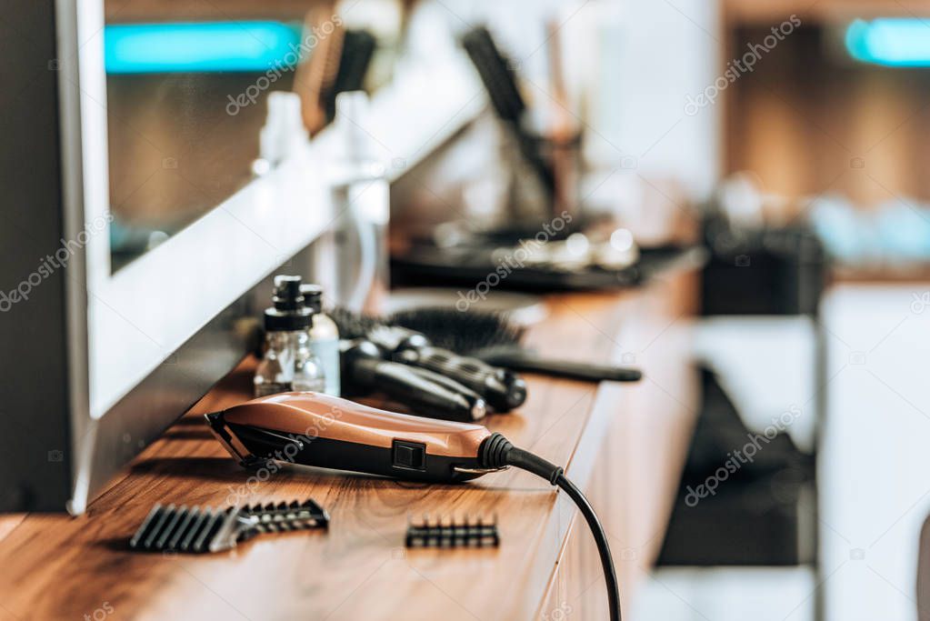 close-up view of electric hair clipper on wooden shelf in beauty salon