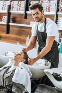 yakışıklı genç Kuaför kadın ve güzellik salonu kamerada bakarak saç yıkama 