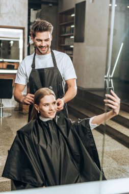 kız alma selfie ile smartphone Kuaför Güzellik Salonu içinde saç kesimi yapıyor iken gülümseyen