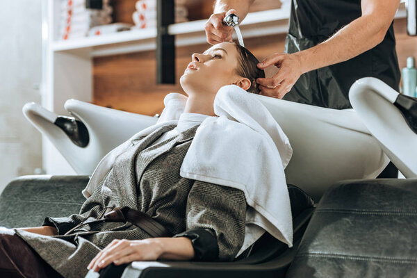 cropped shot of hairdresser washing hair to attractive young woman in beauty salon 