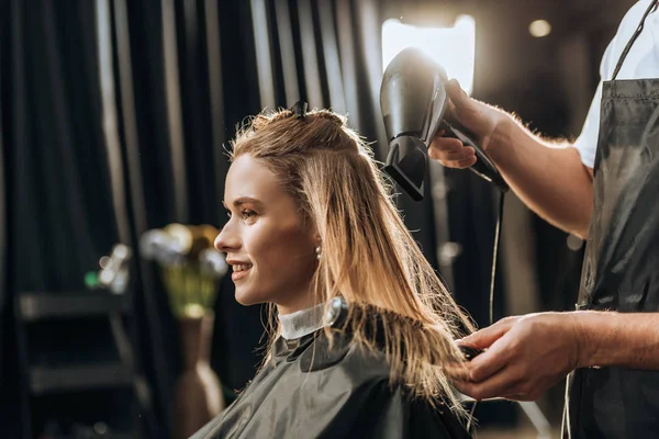 ヘアスタイリストをとかすとビューティー サロンで美しい若い女性に髪を乾燥のクロップ撮影 — ストック写真