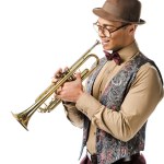 Feliz joven mezclado raza macho jazzman posando con trompeta aislado en blanco