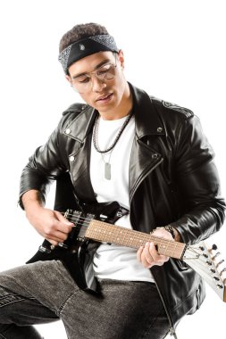 sandalye üzerinde oturan beyaz izole iken elektrik gitar çalmaya deri ceketli erkek rock müzisyeni konsantre