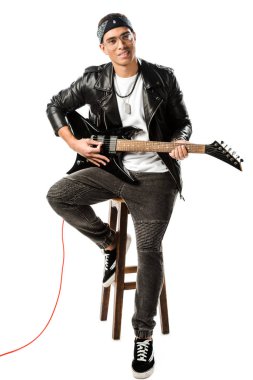 neşeli erkek rock müzisyeni sandalye üzerinde oturan beyaz izole iken elektrik gitar çalmaya deri ceketli