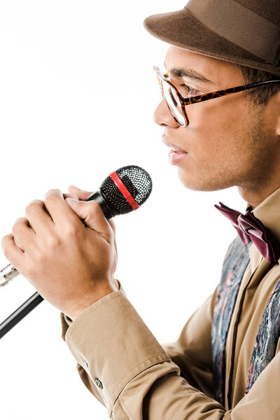 side view of mixed race male musician in hat singing in microphone isolated on white