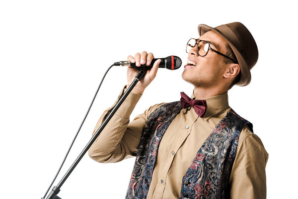 close up shot of emotional stylish mixed race male musician holding microphone and singing isolated on white