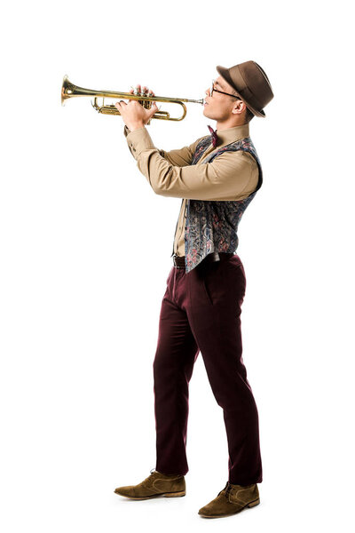 side view of hipster man in hat and eyeglasses playing on trumpet isolated on white 
