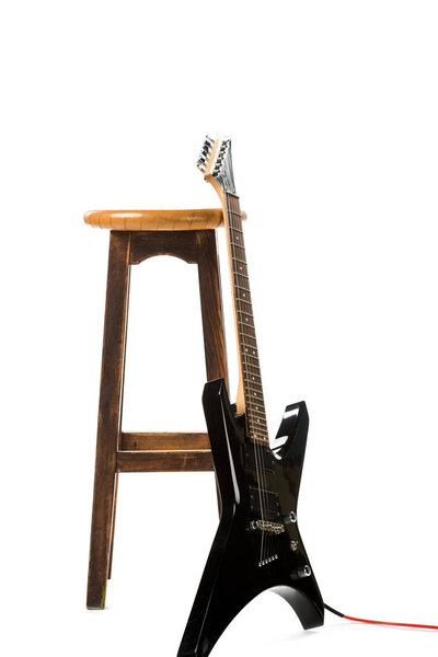 black electric guitar near wooden chair isolated on white