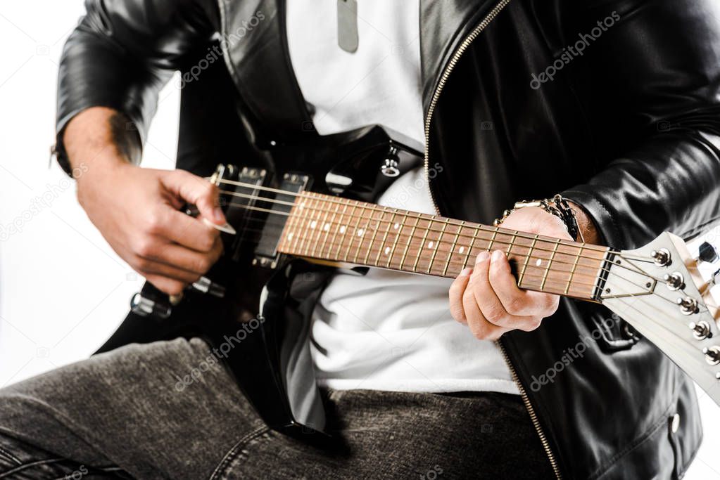 partial view of male rock musician in leather jacket playing on electric guitar isolated on white