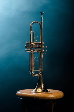 studio shot of trumpet on chair with dramatic lighting background clipart