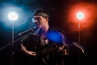 mikrofon şarkı ve elektrik gitar rock konseri sırasında sahne alanı'nda oynamak gülümseyen erkek müzisyen 