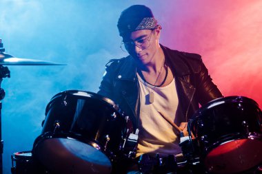 karışık yarış genç adam duman ve dramatik aydınlatma ile sahnede rock konseri sırasında davul çalma