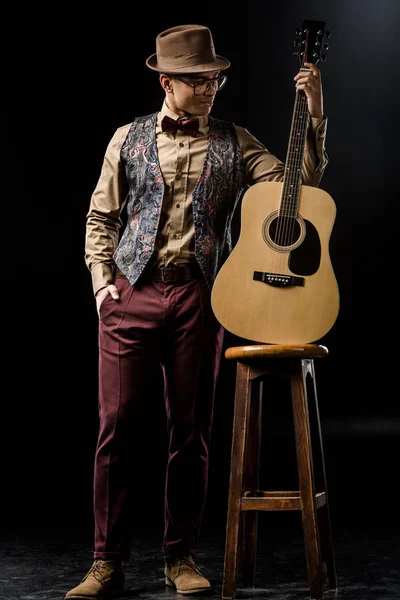 Guapo Elegante Hombre Sombrero Posando Con Guitarra Acústica Cerca Silla — Foto de stock gratuita