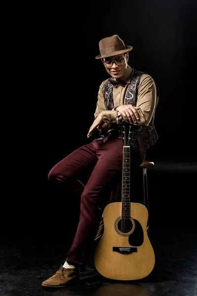 Beautiful Man Stylish Hat Posing Acoustic Guitar While Sitting Chair — Бесплатное стоковое фото