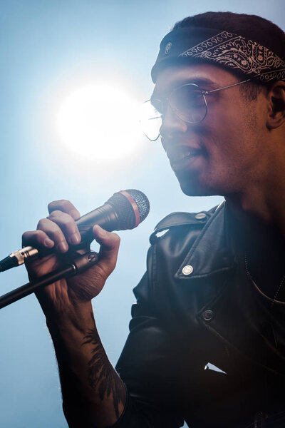 handsome male rock musician singing in microphone on stage with spotlight