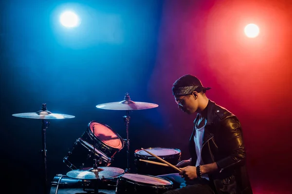 煙とスポット ライトとステージ上のロック コンサート中にドラムの革のジャケットの男性ミュージシャン — ストック写真