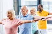 fröhliche multikulturelle Senioren-Athleten beim Synchronturnen im Fitnessstudio