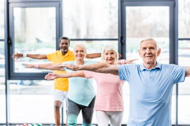 multicultural senior athletes synchronous doing exercise at gym clipart