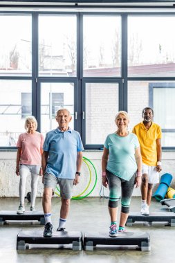 mutlu çok kültürlü üst düzey sporcular spor salonunda adım platformlarda egzersiz zaman uyumlu
