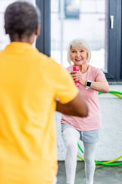 seçici odak olan üst düzey kadın dumbbell vasıl jimnastik salonu ile egzersiz yaparak smartwatch