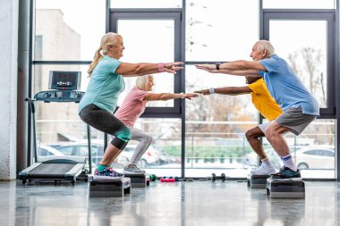 Olgun sporcular spor salonunda adım platformlarda ağız kavgası yapıyor zaman uyumlu yan görünüm