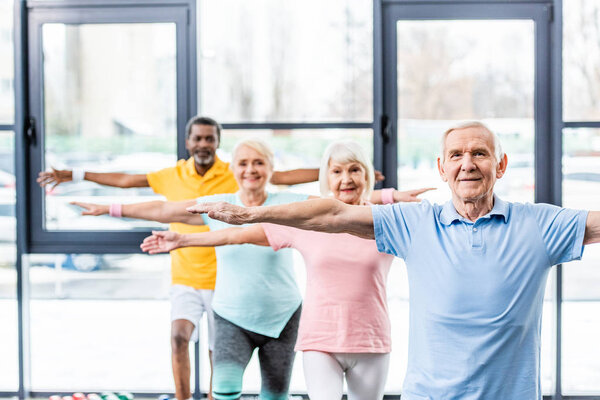 multicultural senior athletes synchronous doing exercise at gym