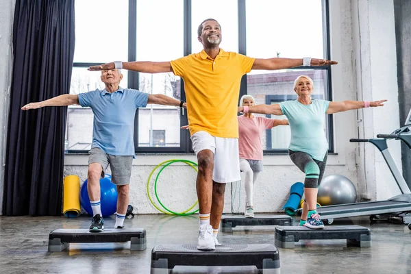 Smiling Senior Multicultural Athletes Synchronous Exercising Step Platforms Gym — Stock Photo, Image