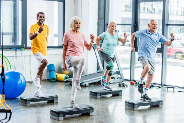 Fröhliche Multiethnische Senioren Beim Synchrontraining Auf Trittbrettern Fitnessstudio — Stockfoto