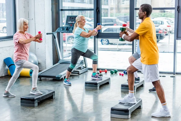 Enfoque Selectivo Deportistas Multiculturales Senior Ejercicio Sincrónico Con Mancuernas Plataformas — Foto de Stock