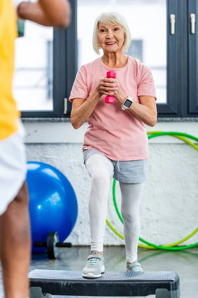 Happy Senior Sportswoman Smartwatch Exercising Dumbbell Step Platform Sports Hall — Stock Photo, Image