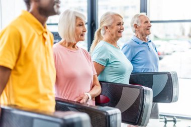 selective focus of senior athletes holding step platforms at gym clipart