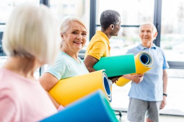 üst düzey sporcumuz fitness mat ve arkadaşları arkasında spor salonunda ayakta tutan seçici odak