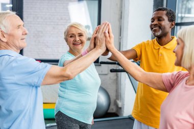 çok kültürlü üst düzey sporcular istifleme gülümseyen birlikte spor salonunda eller