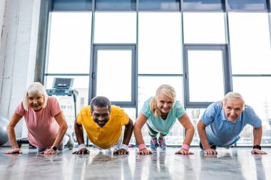 çok ırklı üst düzey sporcu spor salonunda tahta yapıyor zaman uyumlu gülümseyen