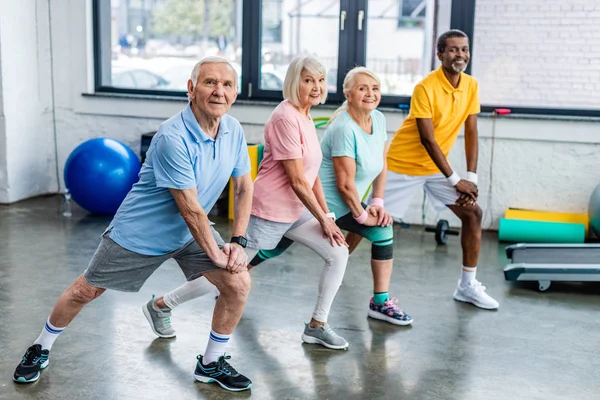 Smiling Senior Multiethnic Sportspeople Synchronous Stretching Sports Hall — Stock Photo, Image